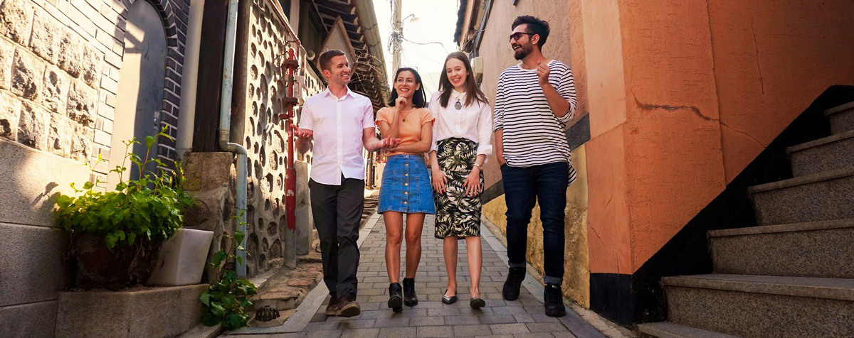 Four friends walking  down a narrow cobblestone street in an old village